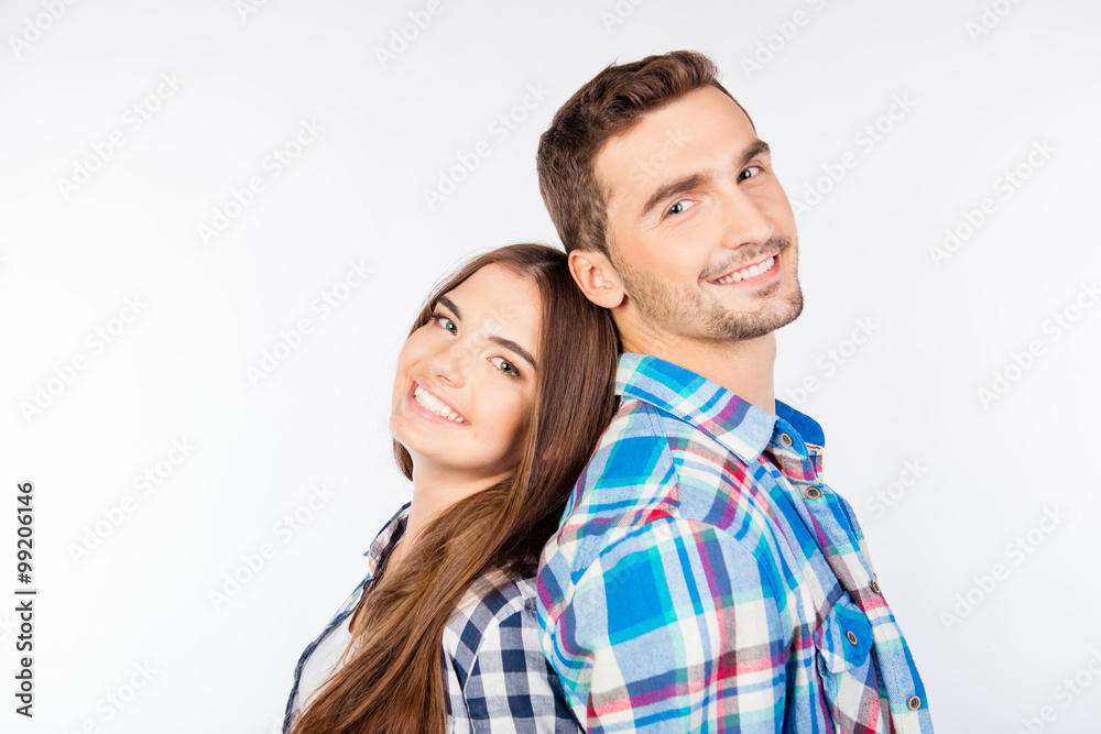 Young smiling couple standing back-to-back Young smiling couple standing back-to-back