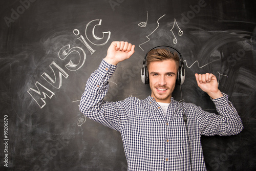 A young student listens to music with head-phones looks up photo