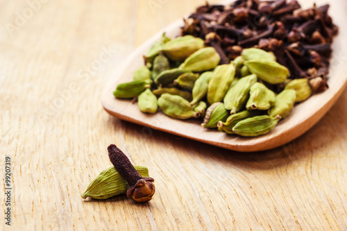 cardamom pods and cloves on wooden spoon