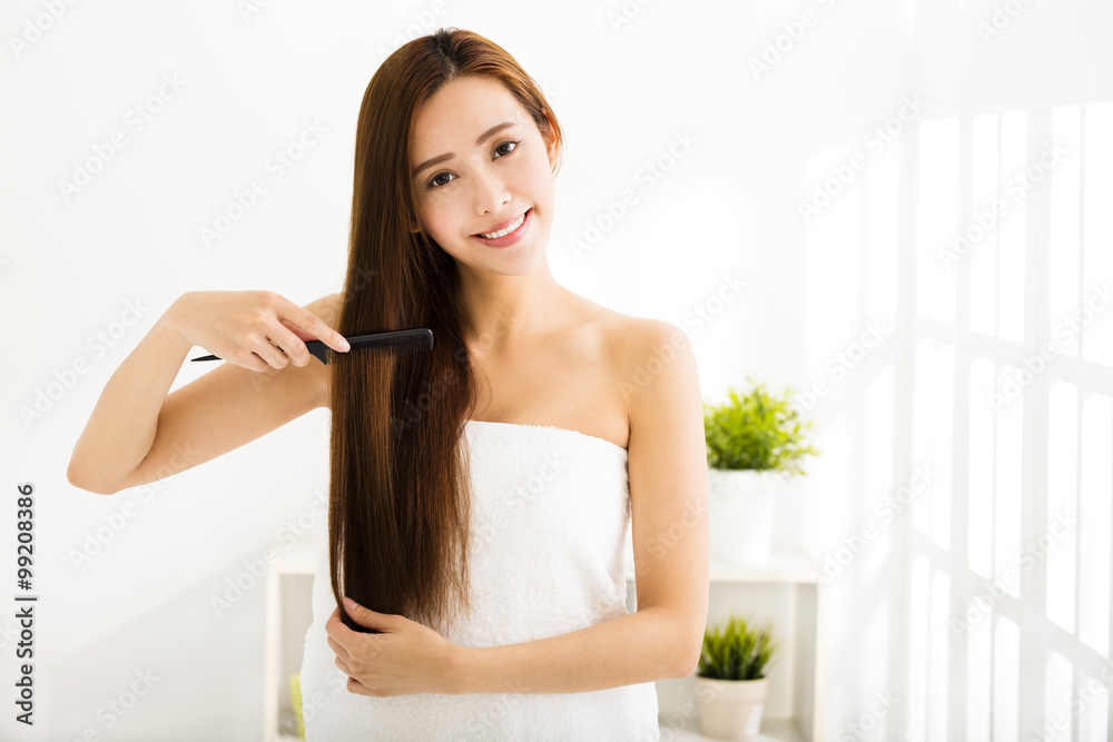 young beautiful woman combing her hair in living room young beautiful woman combing her hair in living room