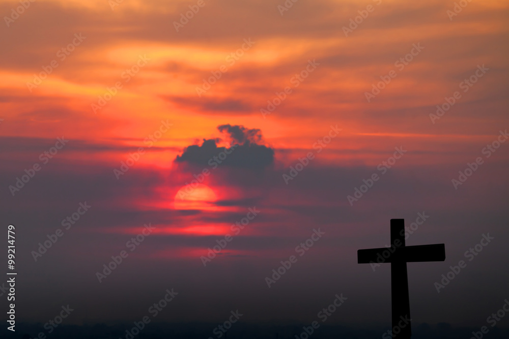 Silhouette of cross over blurred sunset background