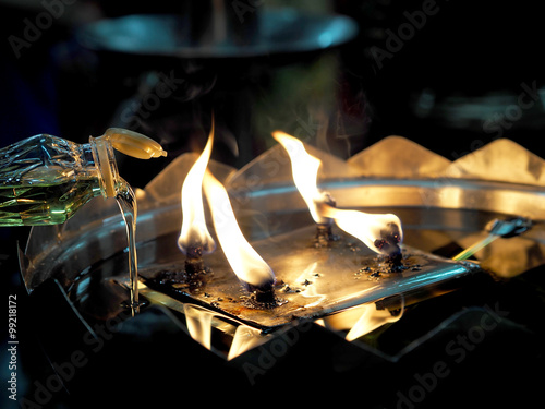 Oil pouring into lamp closeup at the temple photo