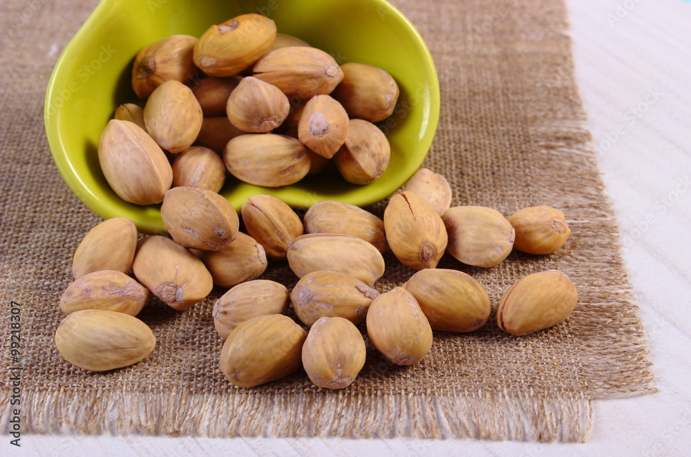 Obraz premium Pistachio nuts in bowl on white wooden table, healthy eating