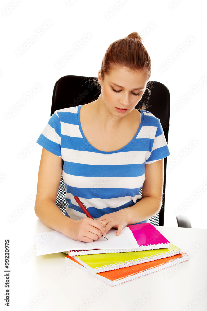 Teenage woman doing homework behind the desk Teenage woman doing homework behind the desk