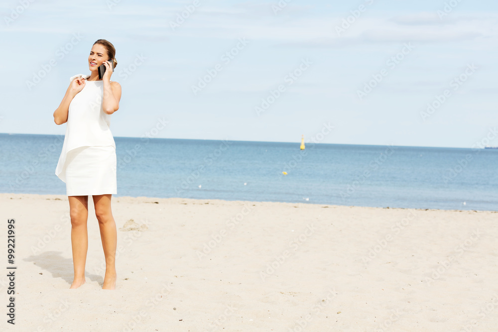 Young elegant beautiful woman talking on the phone on the beach Young elegant beautiful woman talking on the phone on the beach