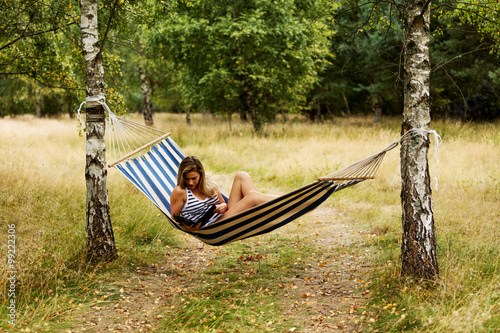 Young woman with tablet on the hammock