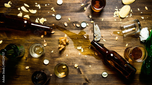 Canvas Print In the process of party - spilled beer, bottle caps and leftover chips on the table