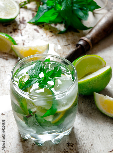 Cocktail in a glass with ice cubes, lime, mint leaves and rum .