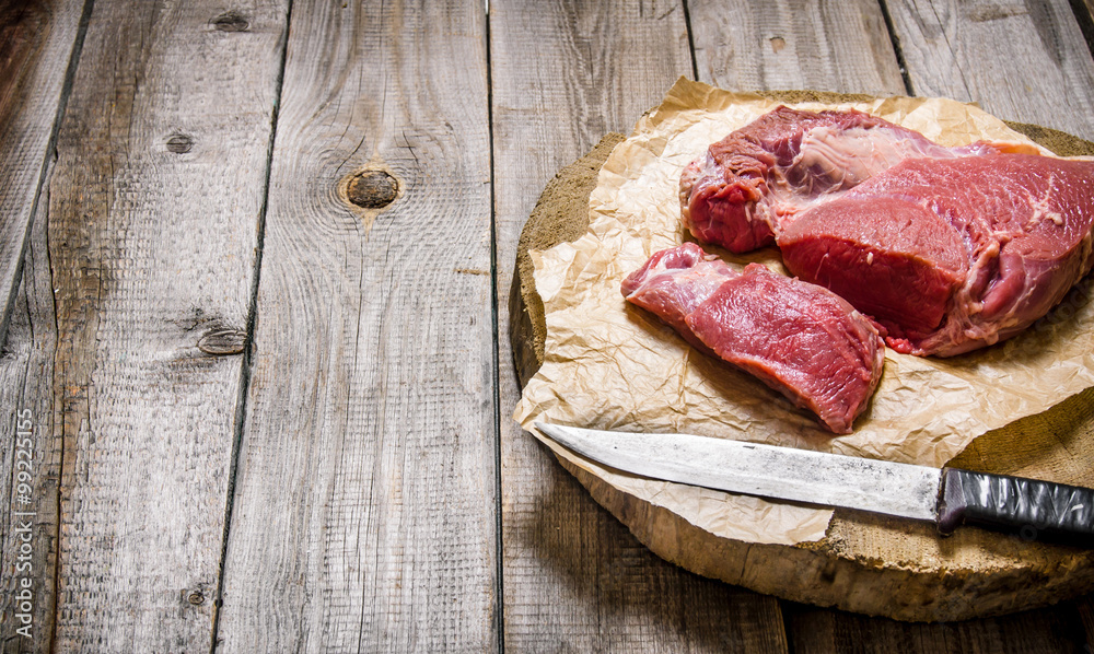 Cutting raw meat a large knife. On wooden table. Cutting raw meat a large knife. On wooden table.