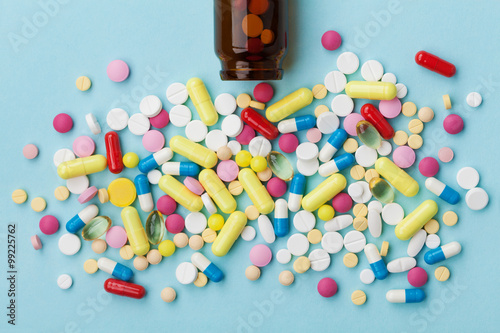 Colorful drug pills on blue background, pharmaceutical concept photo