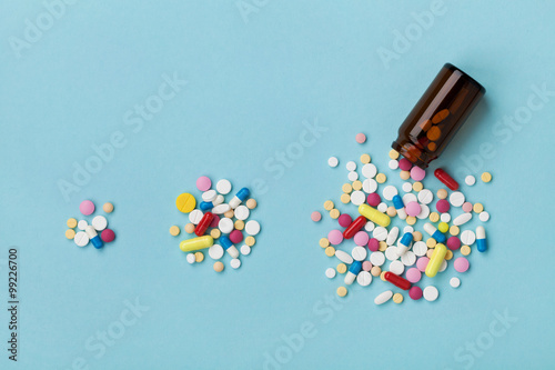 Colorful drug pills on blue background, increasing use and abuse of medication in world concept