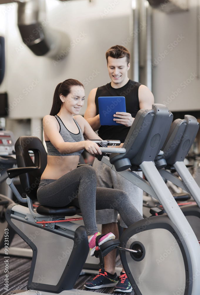 happy woman with trainer on exercise bike in gym happy woman with trainer on exercise bike in gym