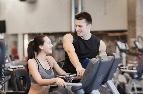 happy woman with trainer on exercise bike in gym