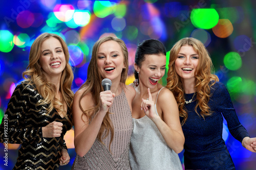 happy young women with microphone singing karaoke