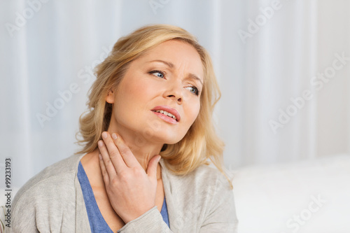 unhappy woman suffering from throat pain at home