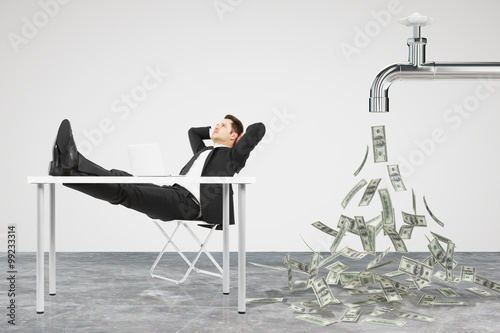 Businessman resting on a chair and faucet from which the money f