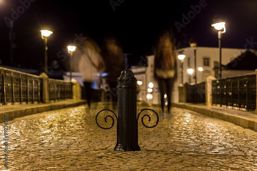 Night street with passers in Tavira. Portugal