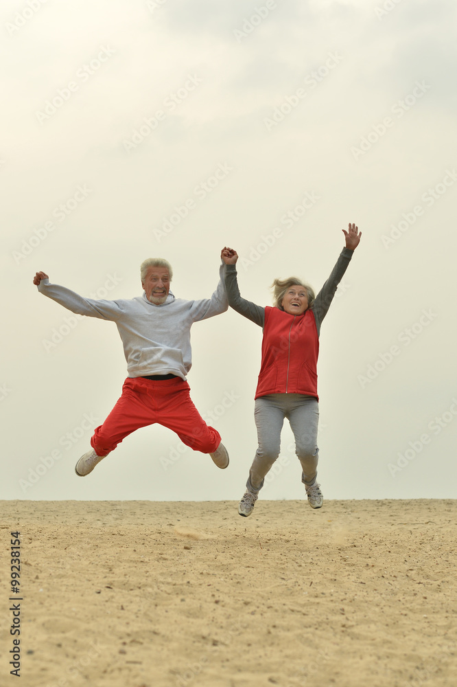Mature couple jumping on beach Mature couple jumping on beach