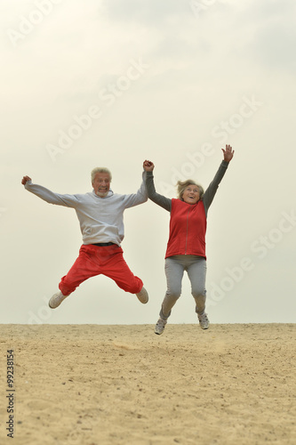 Mature couple jumping on beach