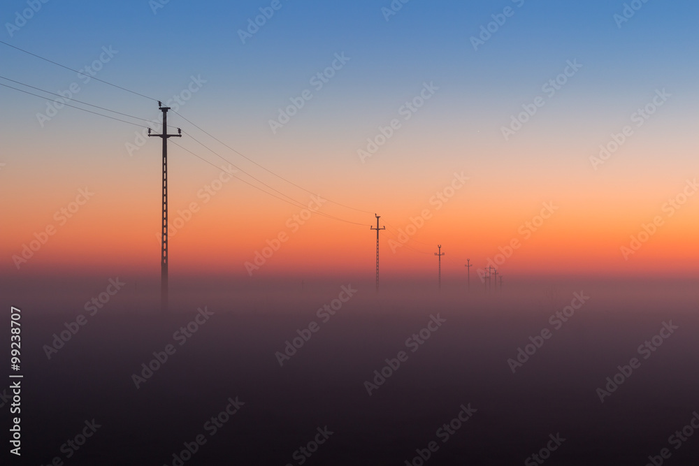 Electrical Power Lines and Pylons disappear over the horizon with Misty Sunrise, Sunset