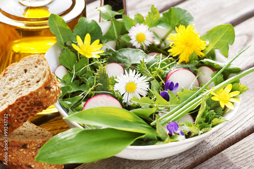 Salat aus Wildkräutern/Frühlingskräutern mit Blüten, Essig und Öl photo