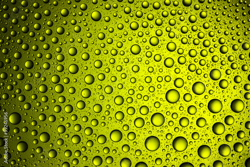 Yellow glass surface covered with water drops texture.