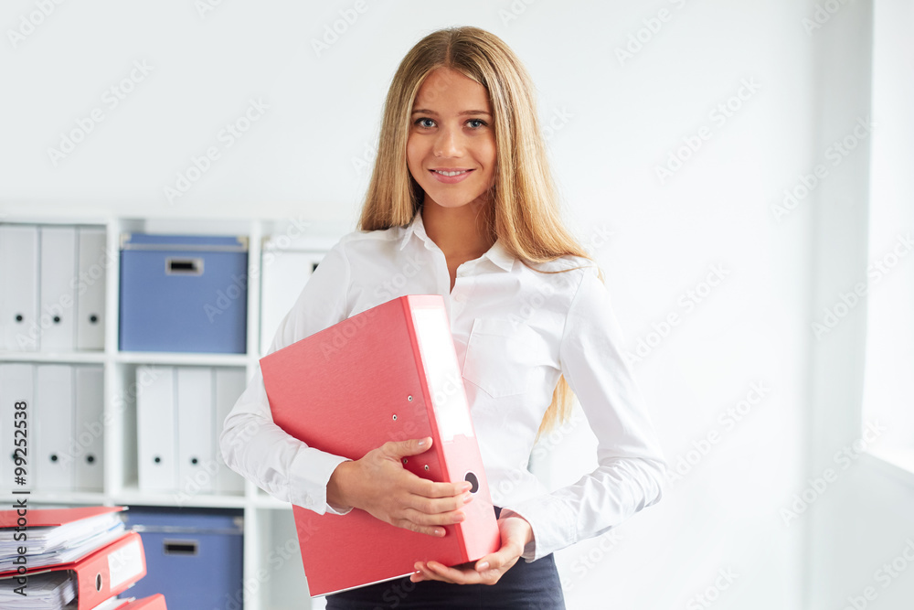 Young business woman standing in office with folders Young business woman standing in office with folders