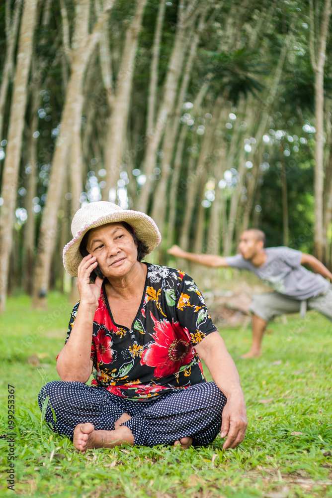 Old woman using mobile phone in garden