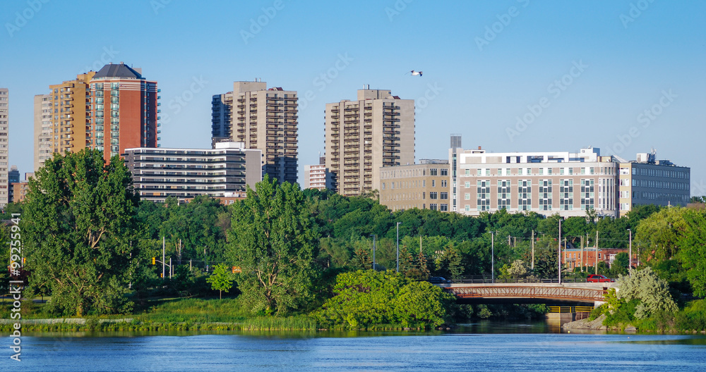 Ottawa River and capitol city skyline along the parkway - late springtime afternoon - early evening approaches.  Tall buildings, apartments and condominiums comprise an Ottawa city skyline.