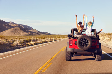 Rear View Of Friends On Road Trip Driving In Convertible Car