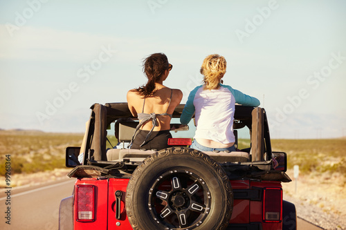 Rear View Of Friends On Road Trip Driving In Convertible Car