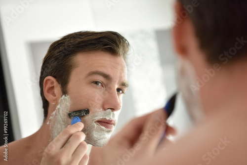 Adult man shaving with foam and manual razer