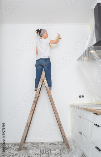 Woman paint wall at home 