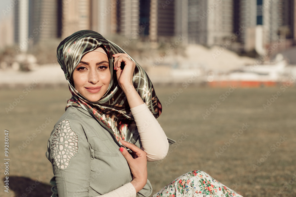 Fototapeta premium Smiling girl in hijab covering her eyes with happiness in Dubai Marina