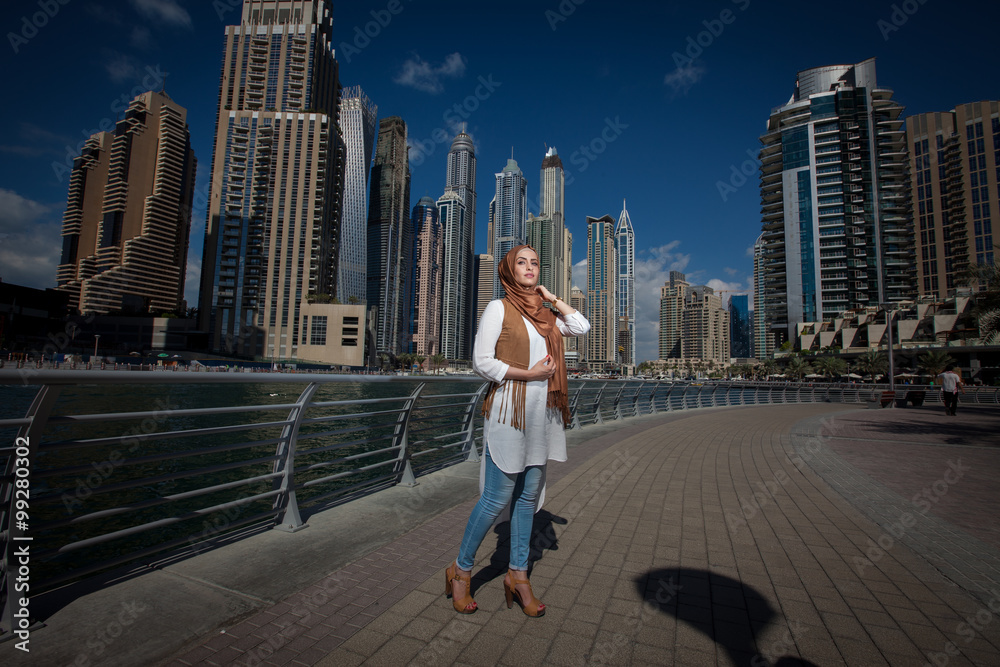 Smiling girl in hijab covering her eyes with happiness in Dubai Marina