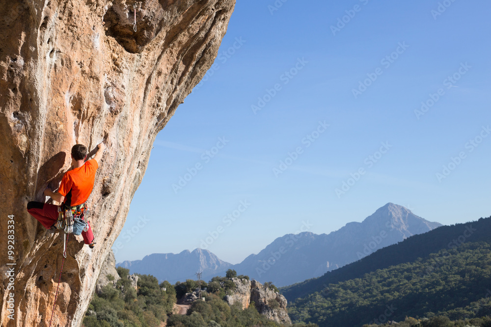 Fototapeta premium Young male climber hanging by a cliff.