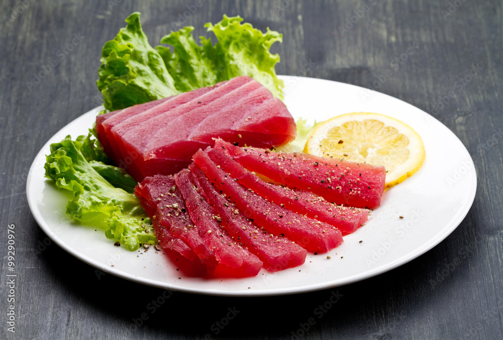 Slices of raw bluefin tuna  sashimi on white dish on wood backgr