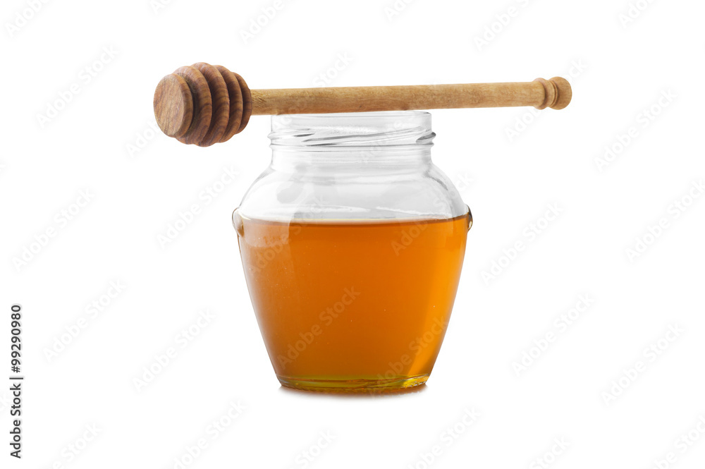 Glass jar of honey with wooden drizzler on a white Glass jar of honey with wooden drizzler on a white