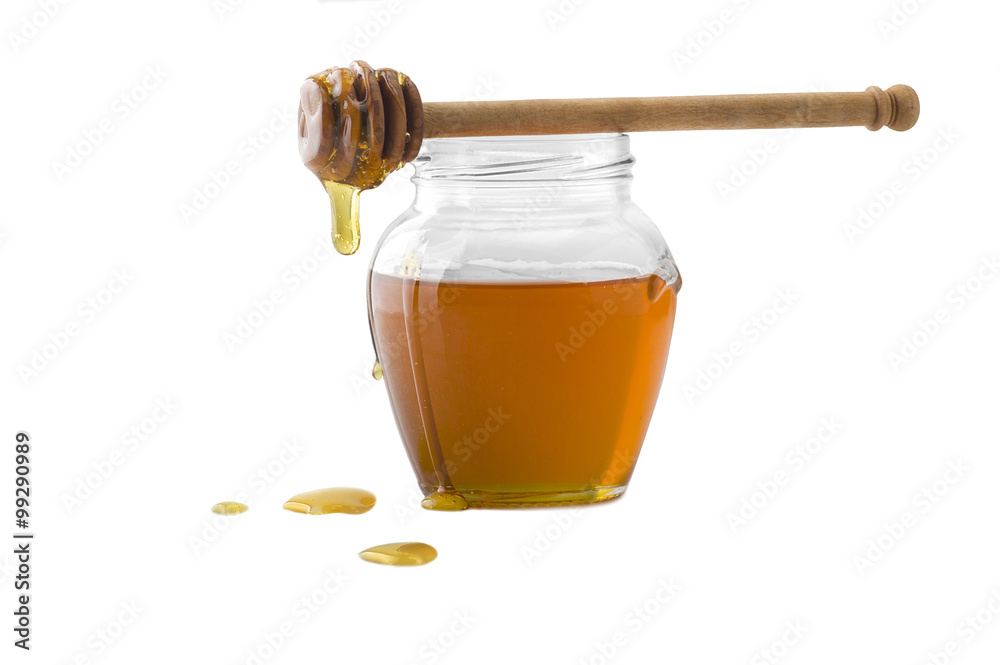 Glass jar of honey with wooden drizzler on a white Glass jar of honey with wooden drizzler on a white