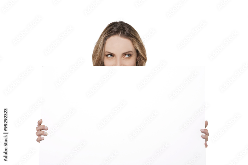 Behind a white board - Woman hiding or peeking behind a white sign Behind a white board - Woman hiding or peeking behind a white sign