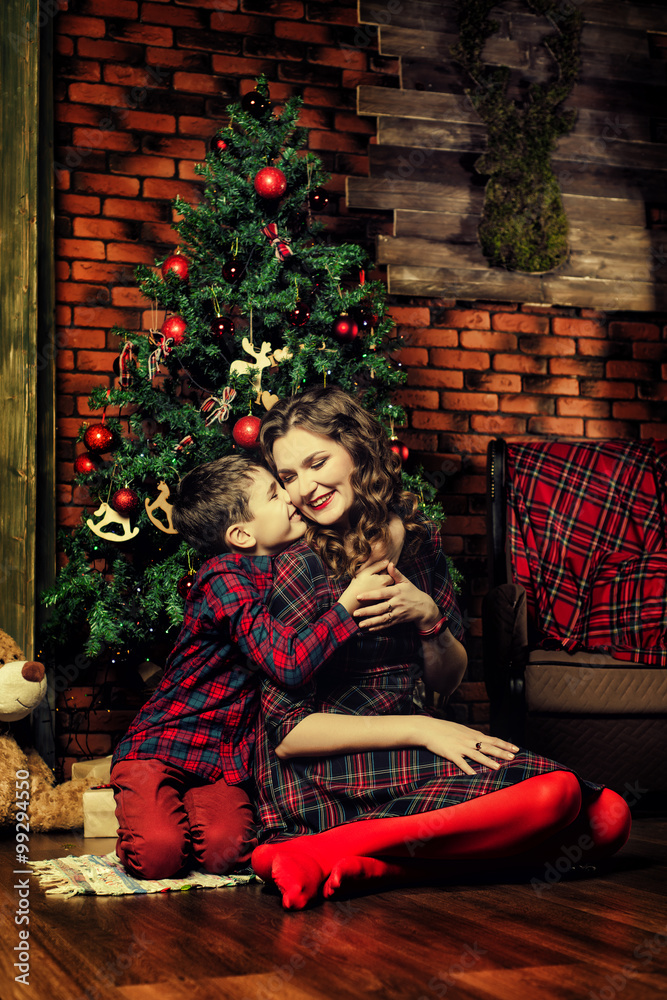 Family celebration of the New Year. The mother and son near a Christmas tree. Giving gifts. Holiday and fun. Family celebration of the New Year. The mother and son near a Christmas tree. Giving gifts. Holiday and fun.