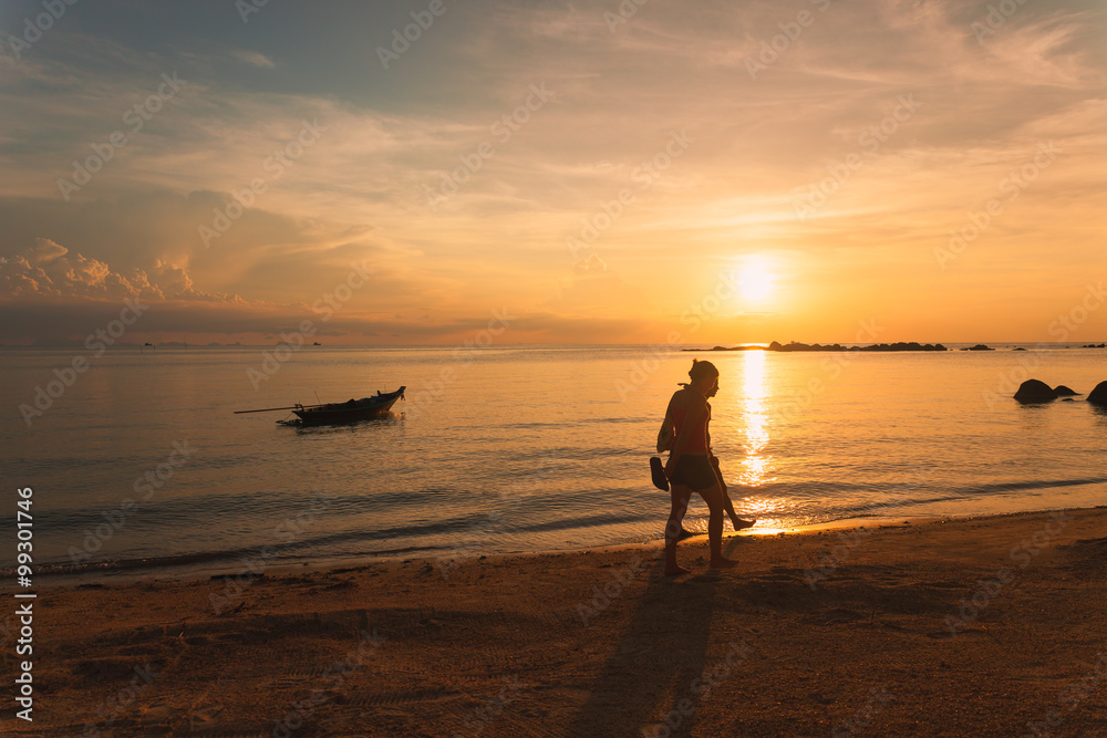 Tourists walk along the beach at sunset in koh Phangan, Thailand