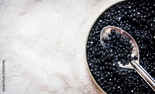 Jar with black caviar and spoon of salt.