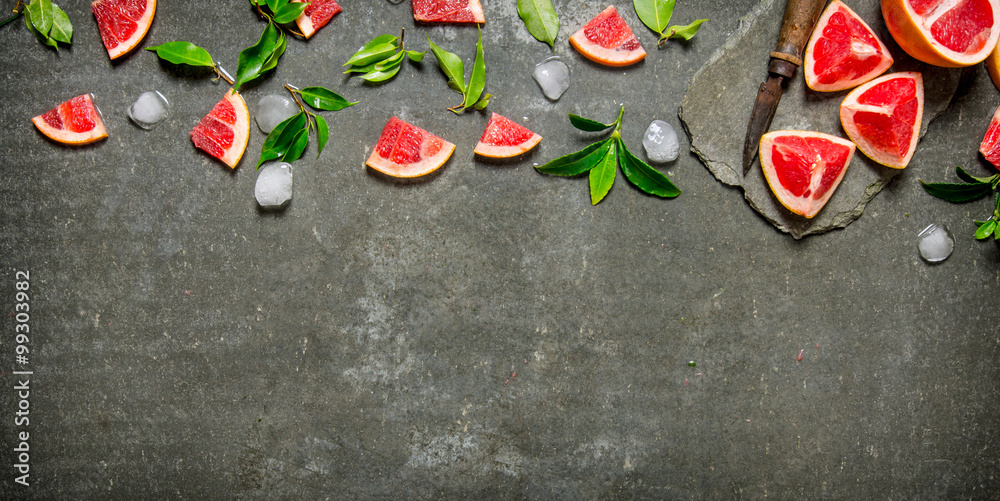 Pieces of sliced grapefruit with leaves and ice.