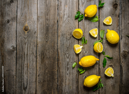 Lemons sliced and whole with leaves .