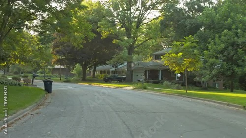 Driving plate: rear view, upscale 1950s-era homes in an affluent Mid West US neighborhood.  Intended for compositing.  24mm lens, stabilized clip, slow speed, recorded in 4K, UHD.
