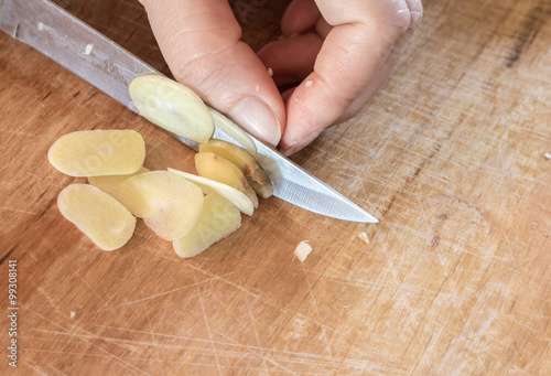Chef slicing garlic on the cutting board with a knife