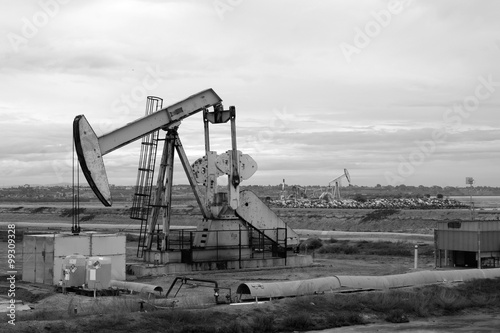 black and white photo of oil derrick with cloudy sky