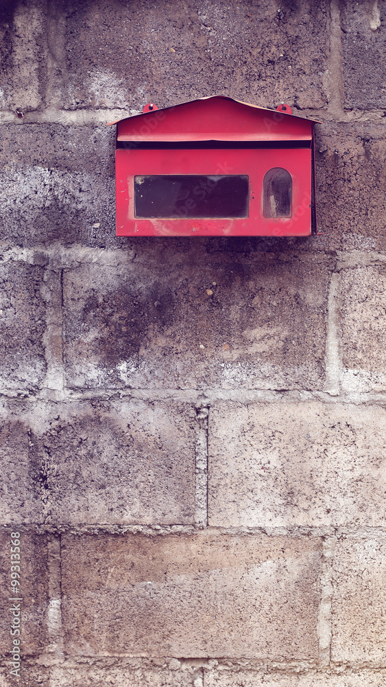 Old red mailbox on concrete wall. Vintage effect.