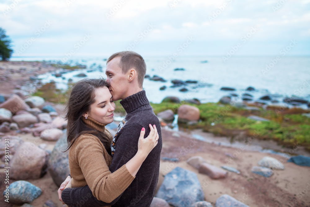 young couple sitting on a rock on the beach
